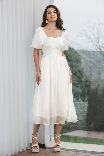 En linje plisserad liten vit klänning med puffärmar